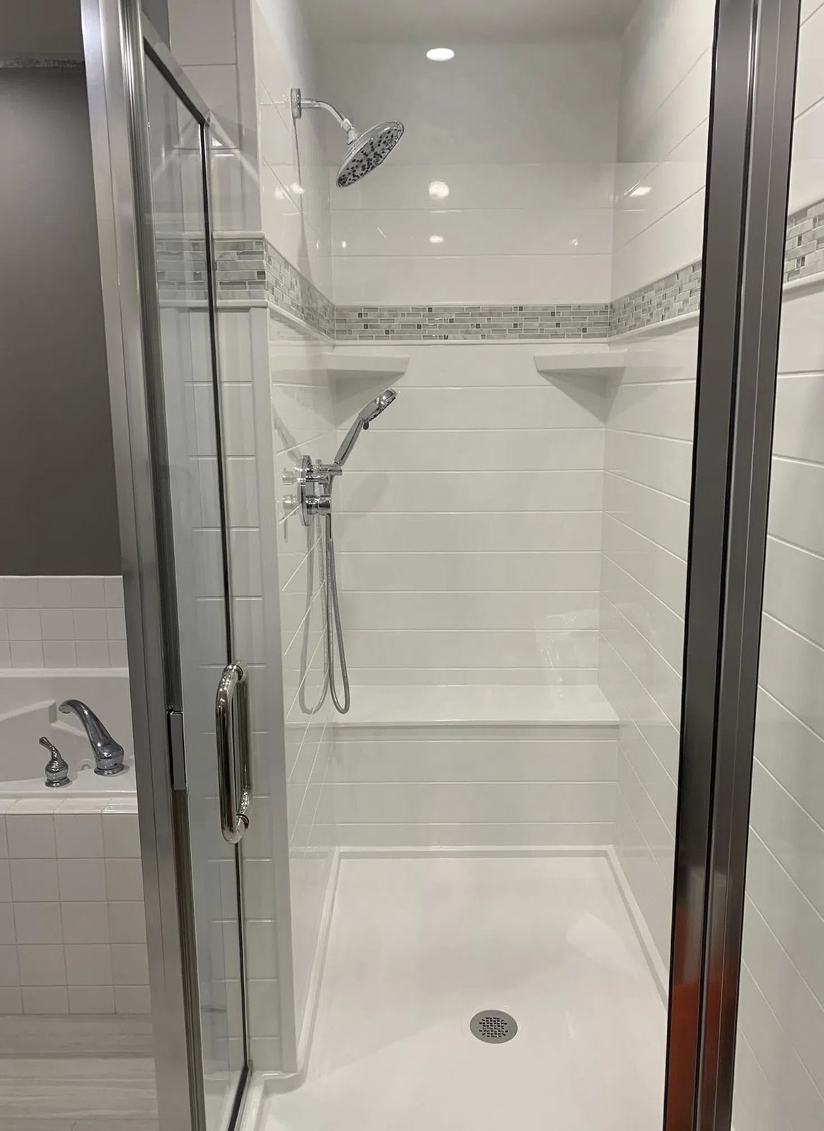 Groutless shower with a mosaic accent band and a sliding glass door, available at Sidney Kitchen and Bath in Winchester, VA
