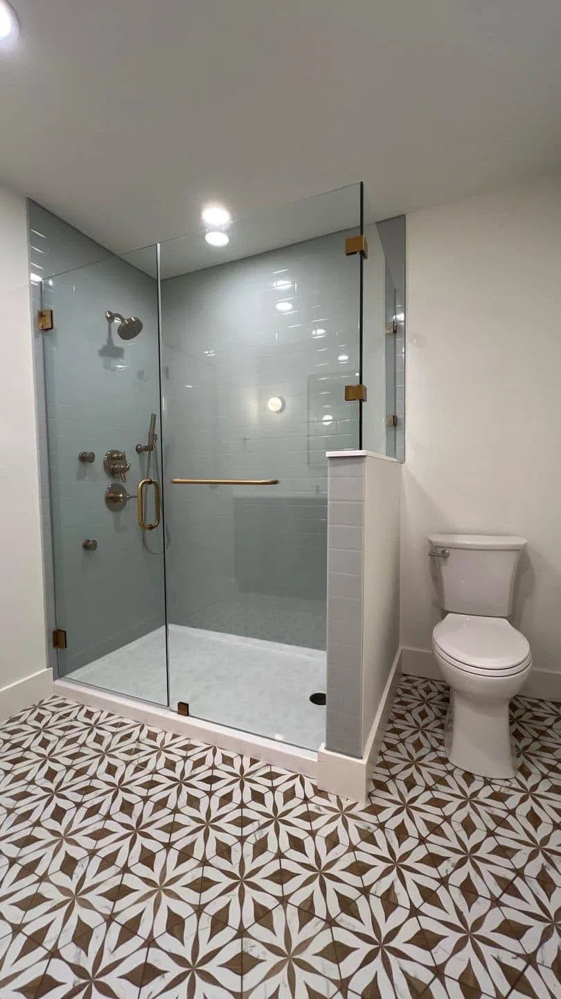 Frameless glass shower with seamless groutless wall panels over a patterned tile floor, available at Sidney Kitchen and Bath in Winchester, VA