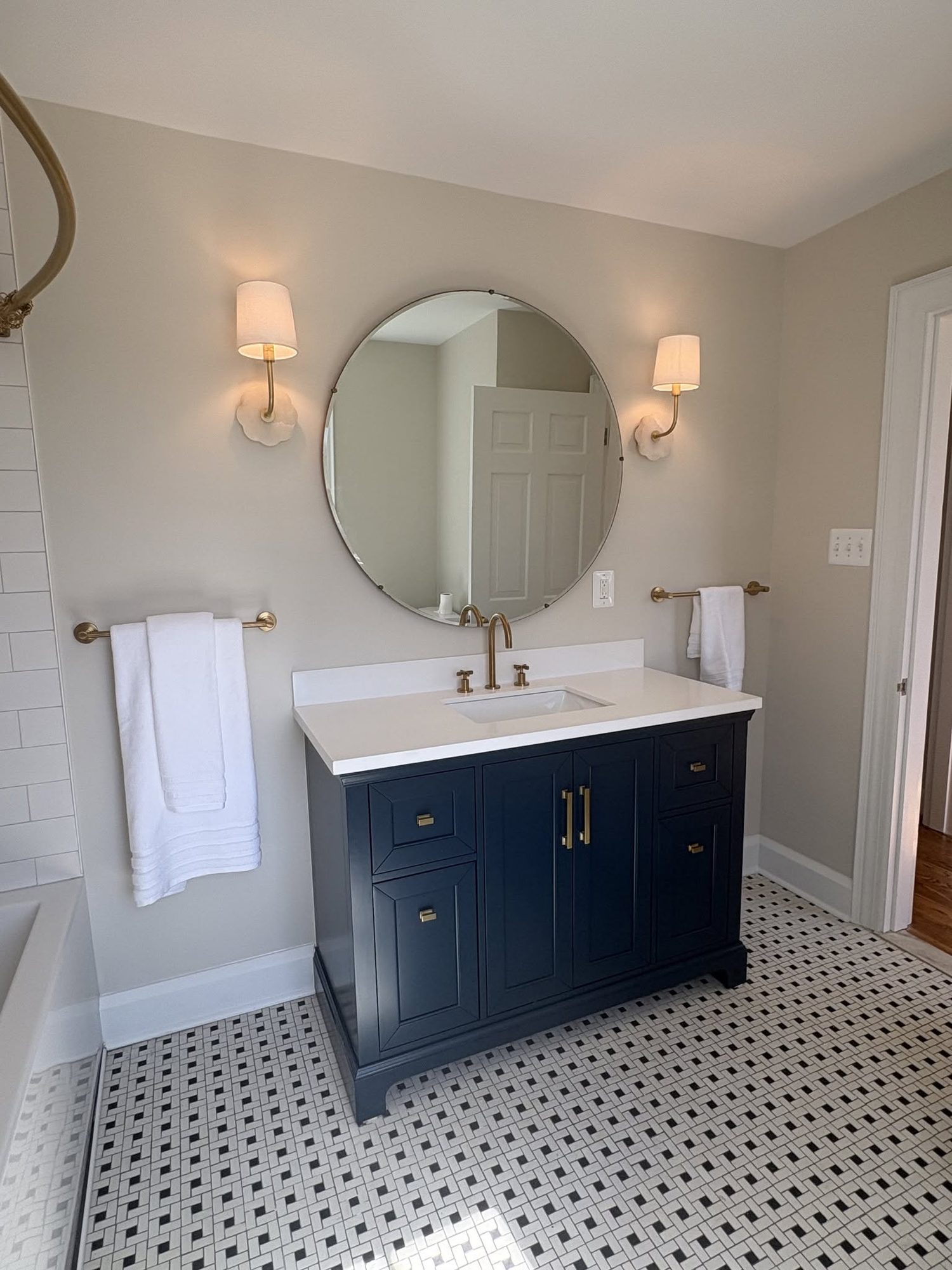 Navy vanity, round mirror, hex tile floor, a bathroom remodel by Sidney Design and Build in Winchester, VA