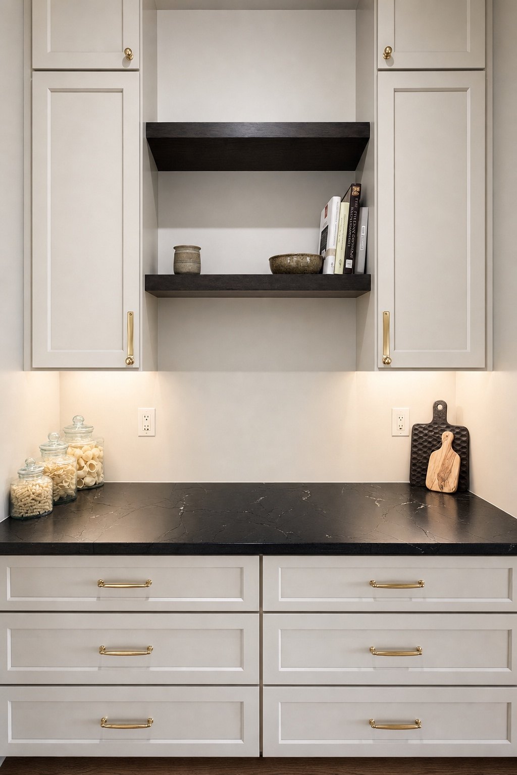 Painted kitchen cabinets with brass pulls, a black countertop and dark floating shelves, by Sidney Design and Build, Winchester, VA