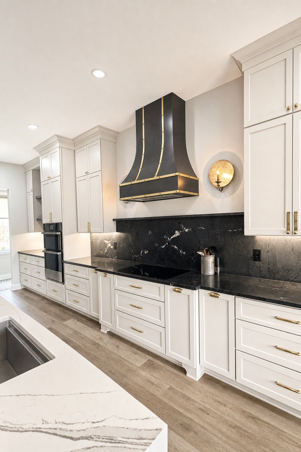 Kitchen cabinet run with black countertops and backsplash, double wall ovens and a custom black and brass range hood, by Sidney Design and Build, Winchester, VA
