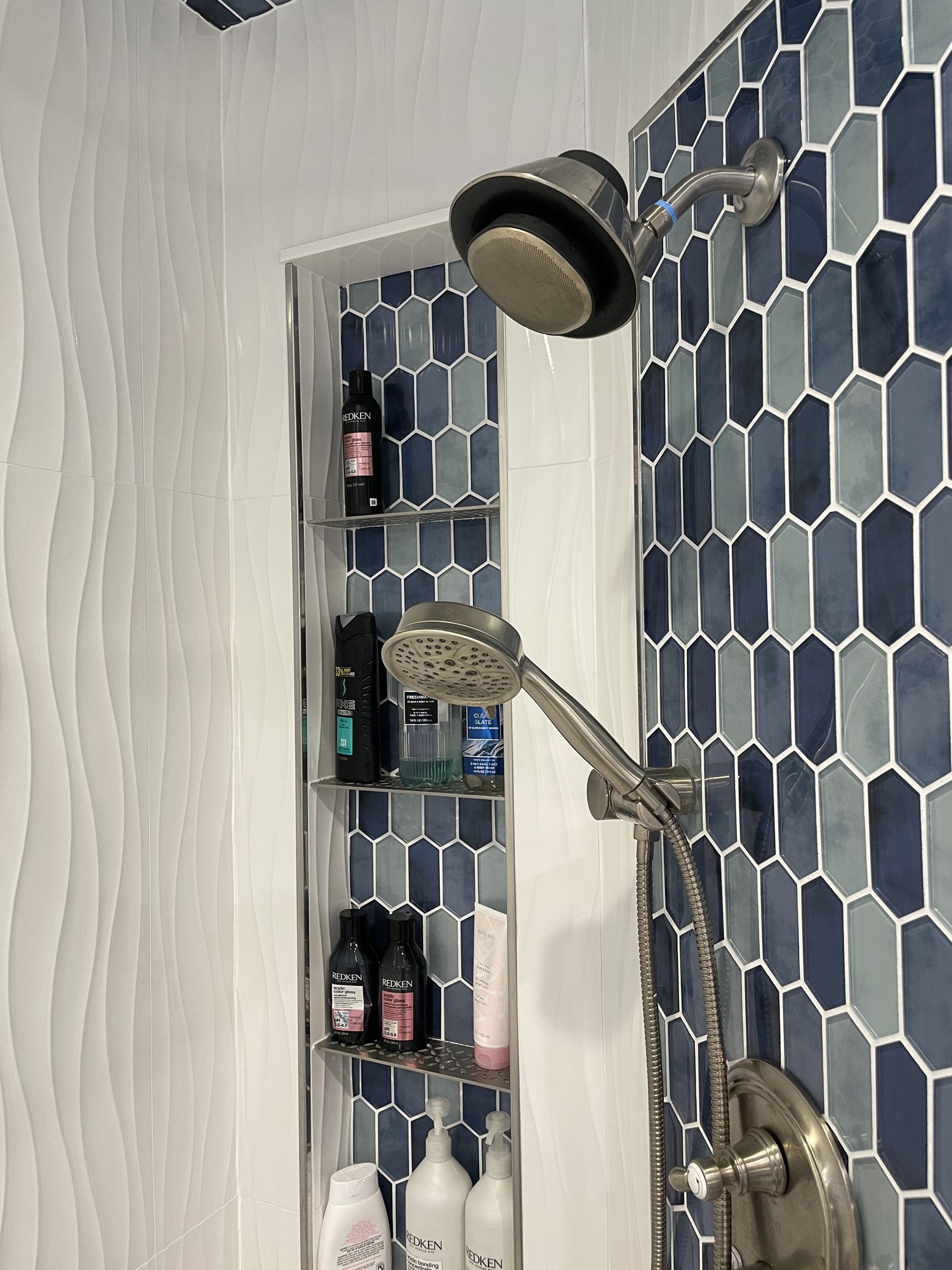 Blue hex tile and a body spray column, a walk in shower by Sidney Design and Build in Winchester, VA