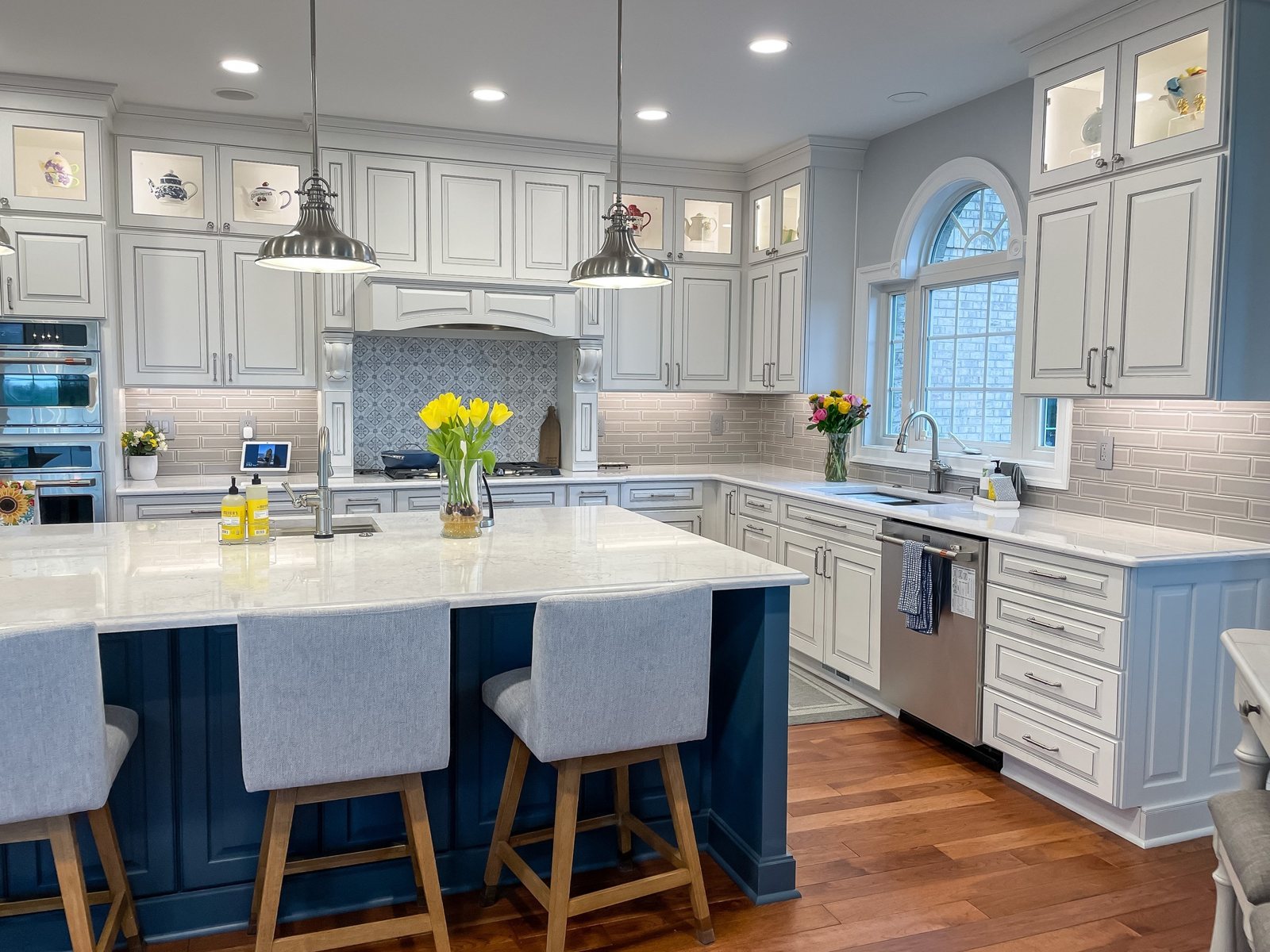 White cabinets and a navy island with cabinet hardware and pendant lights in a Winchester, VA kitchen